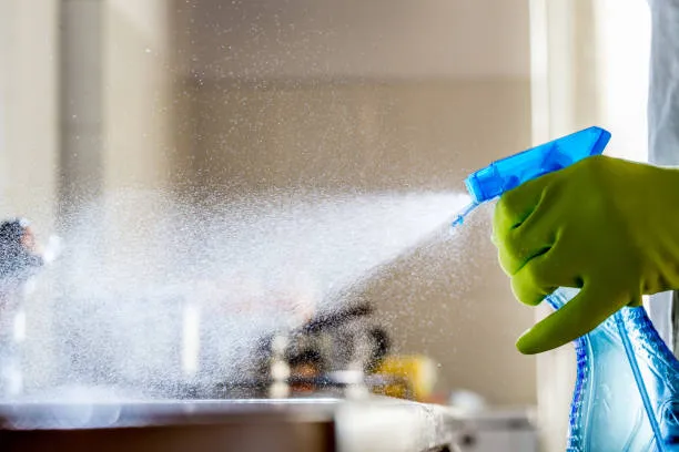 A spray bottle releasing a fine mist on a kitchen surface
