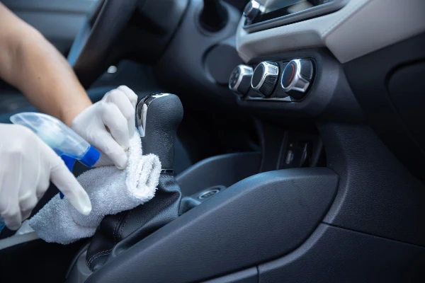 Hand wiping a car gear shifter with a microfiber cloth